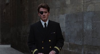 Movie still from “Barcelona” (1994), directed by Whit Stillman – A man in a suit and eye patch; Medium shot, Over the shoulder angle