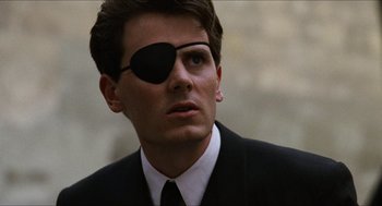 Movie still from “Barcelona” (1994), directed by Whit Stillman – A man wearing a suit and eye patch; Close Up shot, Over the shoulder angle