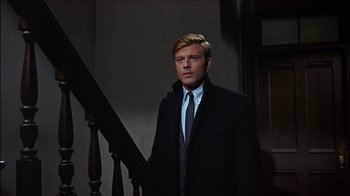 Movie still from “Barefoot in the Park” (1967), directed by Gene Saks – A man wearing a suit and tie standing next to a staircase; Medium shot, Low angle