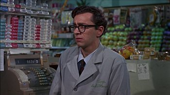 Movie still from “Barefoot in the Park” (1967), directed by Gene Saks – A man wearing a lab coat standing in front of a store; Medium shot, Over the shoulder angle