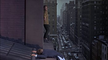 Movie still from “Barefoot in the Park” (1967), directed by Gene Saks – A man laying on the roof of a building next to another man standing on a ledge; Wide shot, Overhead angle