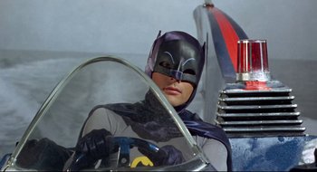 Movie still from “Batman: The Movie” (1966), directed by Leslie H. Martinson – A man wearing a batman mask sitting behind a steering wheel; Medium shot, Low angle