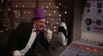 Movie still from “Batman: The Movie” (1966), directed by Leslie H. Martinson – A man wearing a purple hat and a purple tie and a penguin; Medium shot, Low angle