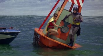 Movie still from “Batman: The Movie” (1966), directed by Leslie H. Martinson – A woman and a man dressed as batman and robin on a boat in the ocean; Wide shot, Low angle