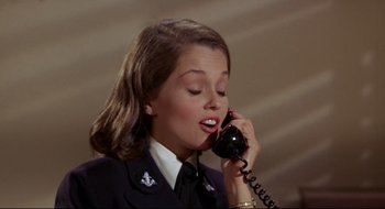 Movie still from “Batman: The Movie” (1966), directed by Leslie H. Martinson – A woman in uniform talking on a phone; Close Up shot, Low angle