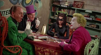 Movie still from “Batman: The Movie” (1966), directed by Leslie H. Martinson – A group of people sitting around a table; Medium shot, High angle