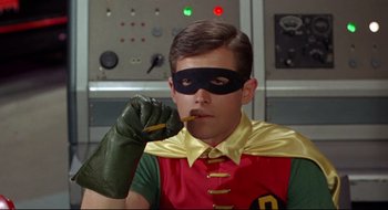 Movie still from “Batman: The Movie” (1966), directed by Leslie H. Martinson – A young man dressed as robin holding a pencil in his mouth; Close Up shot, Low angle