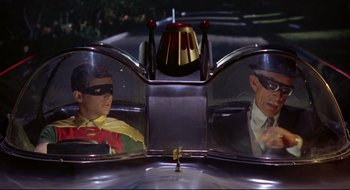 Movie still from “Batman: The Movie” (1966), directed by Leslie H. Martinson – A man and a woman in the mirror of a car; Medium shot, High angle