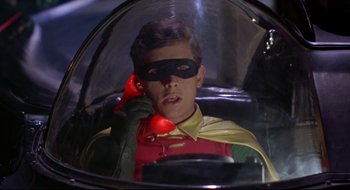 Movie still from “Batman: The Movie” (1966), directed by Leslie H. Martinson – A young man wearing a red and yellow cape and a red mask; Close Up shot, Low angle