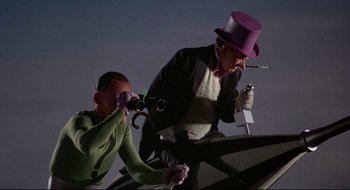 Movie still from “Batman: The Movie” (1966), directed by Leslie H. Martinson – A man in a purple hat and a man in a green shirt; Medium shot, Low angle