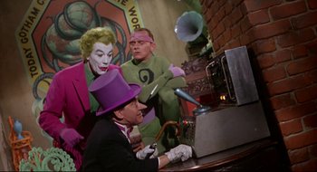 Movie still from “Batman: The Movie” (1966), directed by Leslie H. Martinson – A group of people in costumes at a table; Medium shot, Low angle