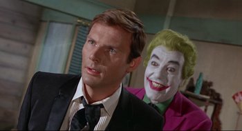 Movie still from “Batman: The Movie” (1966), directed by Leslie H. Martinson – A man in a suit and tie next to another man in a joker costume; Close Up shot, Over the shoulder angle