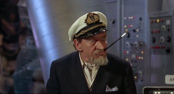 Movie still from “Batman: The Movie” (1966), directed by Leslie H. Martinson – An old man wearing a hat and smoking a pipe; Medium shot, Low angle