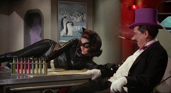Movie still from “Batman: The Movie” (1966), directed by Leslie H. Martinson – A woman dressed as a cat is laying on a table; Medium shot, Low angle