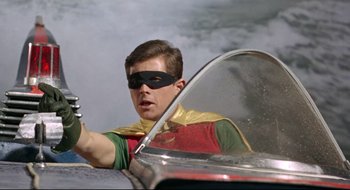 Movie still from “Batman: The Movie” (1966), directed by Leslie H. Martinson – A young man in a batman costume driving a car; Medium shot, Low angle