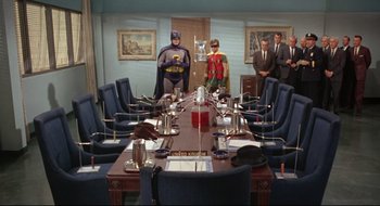 Movie still from “Batman: The Movie” (1966), directed by Leslie H. Martinson – A room filled with tables and chairs and people standing around it; Wide shot, High angle