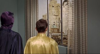 Movie still from “Batman: The Movie” (1966), directed by Leslie H. Martinson – A man wearing a gold cape looking out a window; Medium shot, Low angle