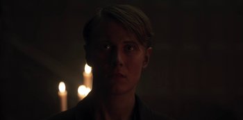 Movie still from “Dark” (2017), created by Baran bo Odar – A man in a dark room with candles in the background; Close Up shot, Low angle