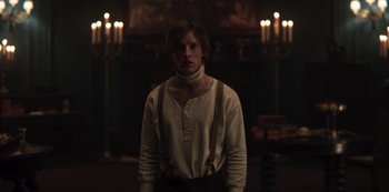 Movie still from “Dark” (2017), created by Baran bo Odar – A man standing in front of candles in a dark room; Medium shot, Over the shoulder angle
