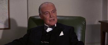 Movie still from “The Battle of Britain” (1969), directed by Guy Hamilton – An older man wearing a suit and bow tie; Close Up shot, Low angle