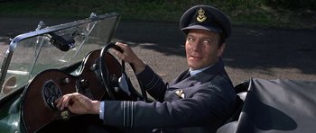 Movie still from “The Battle of Britain” (1969), directed by Guy Hamilton – A man in a uniform sitting in the driver's seat of a car; Close Up shot, Low angle