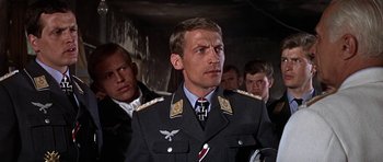 Movie still from “The Battle of Britain” (1969), directed by Guy Hamilton – A group of men standing next to each other in a room; Close Up shot, Low angle