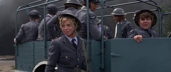Movie still from “The Battle of Britain” (1969), directed by Guy Hamilton – A woman in a military uniform standing in front of a group of men; Medium shot, Over the shoulder angle