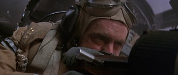 Movie still from “The Battle of Britain” (1969), directed by Guy Hamilton – An older man wearing a helmet and goggles while holding a gun; Close Up shot, Low angle
