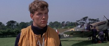 Movie still from “The Battle of Britain” (1969), directed by Guy Hamilton – A man standing in front of an airplane in a field; Close Up shot, Low angle