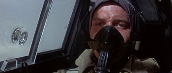 Movie still from “The Battle of Britain” (1969), directed by Guy Hamilton – A man wearing a gas mask and holding a fork in his mouth; Close Up shot, Low angle