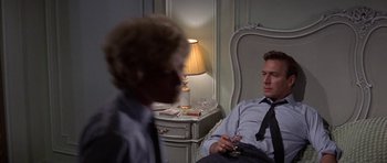 Movie still from “The Battle of Britain” (1969), directed by Guy Hamilton – A man sitting in a chair talking to another man; Medium shot, Over the shoulder angle