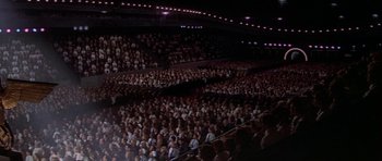 Movie still from “The Battle of Britain” (1969), directed by Guy Hamilton – A large group of people are in a large auditorium; Extreme Wide shot, High angle