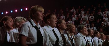 Movie still from “The Battle of Britain” (1969), directed by Guy Hamilton – A group of people wearing ties and white shirts in front of a crowd; Medium shot, Low angle