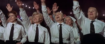Movie still from “The Battle of Britain” (1969), directed by Guy Hamilton – A group of older people with their hands raised; Medium shot, Low angle
