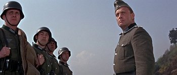 Movie still from “The Battle of Britain” (1969), directed by Guy Hamilton – A group of men standing next to each other in uniforms; Medium shot, Low angle