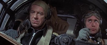 Movie still from “The Battle of Britain” (1969), directed by Guy Hamilton – A man in a helmet and a leather jacket in an airplane; Close Up shot, Low angle