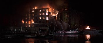 Movie still from “The Battle of Britain” (1969), directed by Guy Hamilton – A large building on fire in a city at night; Extreme Wide shot, High angle