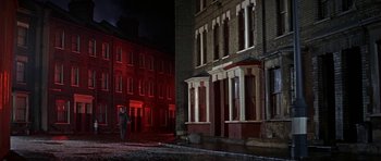 Movie still from “The Battle of Britain” (1969), directed by Guy Hamilton – A person standing in front of a building at night; Extreme Wide shot, Low angle