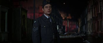 Movie still from “The Battle of Britain” (1969), directed by Guy Hamilton – A man in a uniform standing in front of a building at night; Medium shot, Low angle