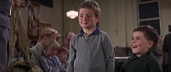 Movie still from “The Battle of Britain” (1969), directed by Guy Hamilton – A young boy in a grey sweater and a tie; Medium shot, Low angle