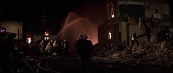Movie still from “The Battle of Britain” (1969), directed by Guy Hamilton – A fire hydrant spewing water into the air near a building; Wide shot, High angle