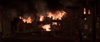 Movie still from “The Battle of Britain” (1969), directed by Guy Hamilton – A building on fire at night with smoke billowing from it; Extreme Wide shot, High angle