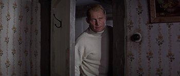 Movie still from “The Battle of Britain” (1969), directed by Guy Hamilton – A man wearing a white sweater standing in a doorway; Medium shot, Low angle