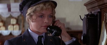 Movie still from “The Battle of Britain” (1969), directed by Guy Hamilton – A woman talking on a phone while wearing a hat; Close Up shot, High angle