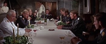Movie still from “The Battle of Britain” (1969), directed by Guy Hamilton – A group of people sitting at a table with food; Medium shot, High angle