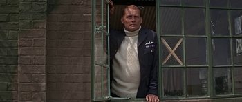 Movie still from “The Battle of Britain” (1969), directed by Guy Hamilton – A man standing in front of an open window; Medium shot, Low angle