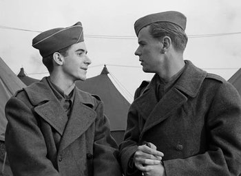 Movie still from “Battleground” (1949), directed by William A. Wellman – A couple of men standing next to each other; Medium shot, Over the shoulder angle