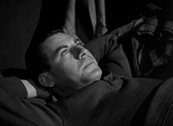 Movie still from “Battleground” (1949), directed by William A. Wellman – A black and white photo of a man laying on his stomach; Close Up shot, High angle