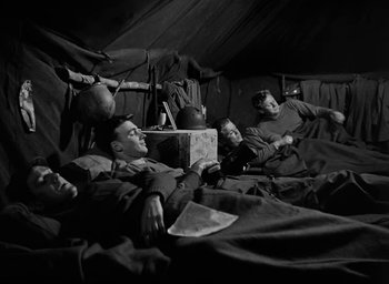 Movie still from “Battleground” (1949), directed by William A. Wellman – A black and white photo of a group of soldiers in a tent; Medium shot, High angle