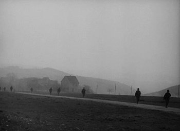 Movie still from “Battleground” (1949), directed by William A. Wellman – A black and white photo of people walking on a dirt road; Extreme Wide shot, Low angle